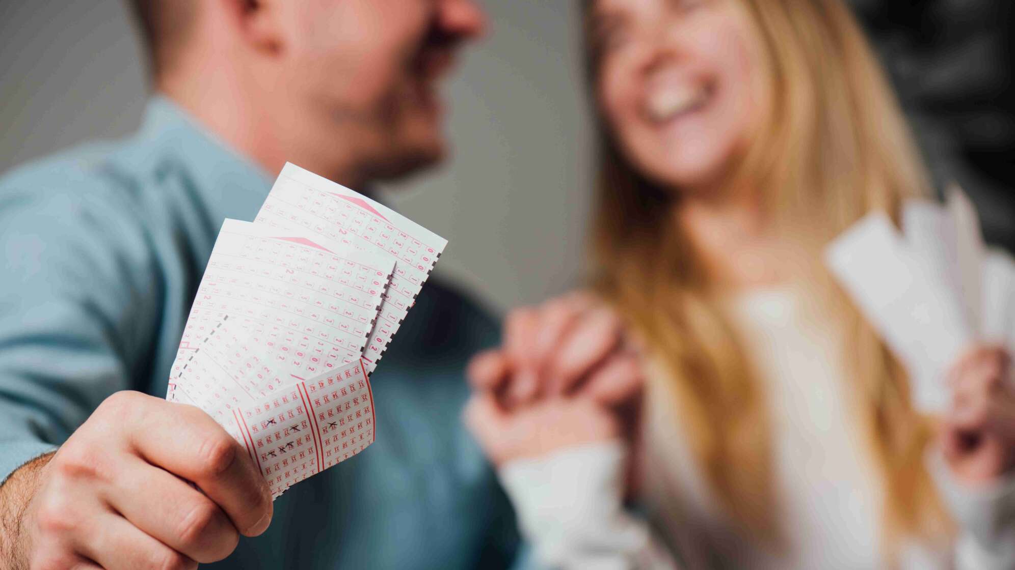 Mann und Frau lachen mit Lottoscheinen