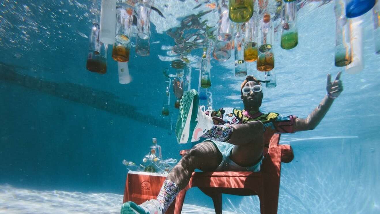 Unterwasserbild mit Getränkeflaschen und im Wasser sitzenden Mann