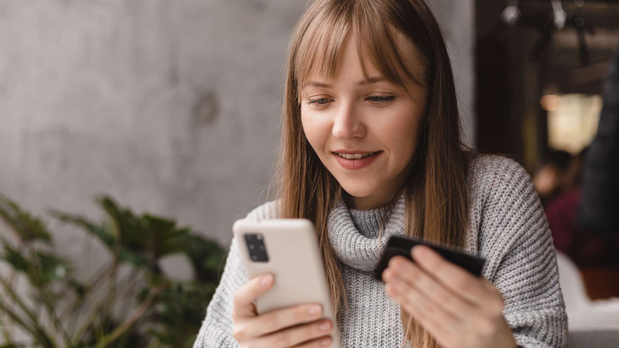 Frau am Handy mit Kreditkarte