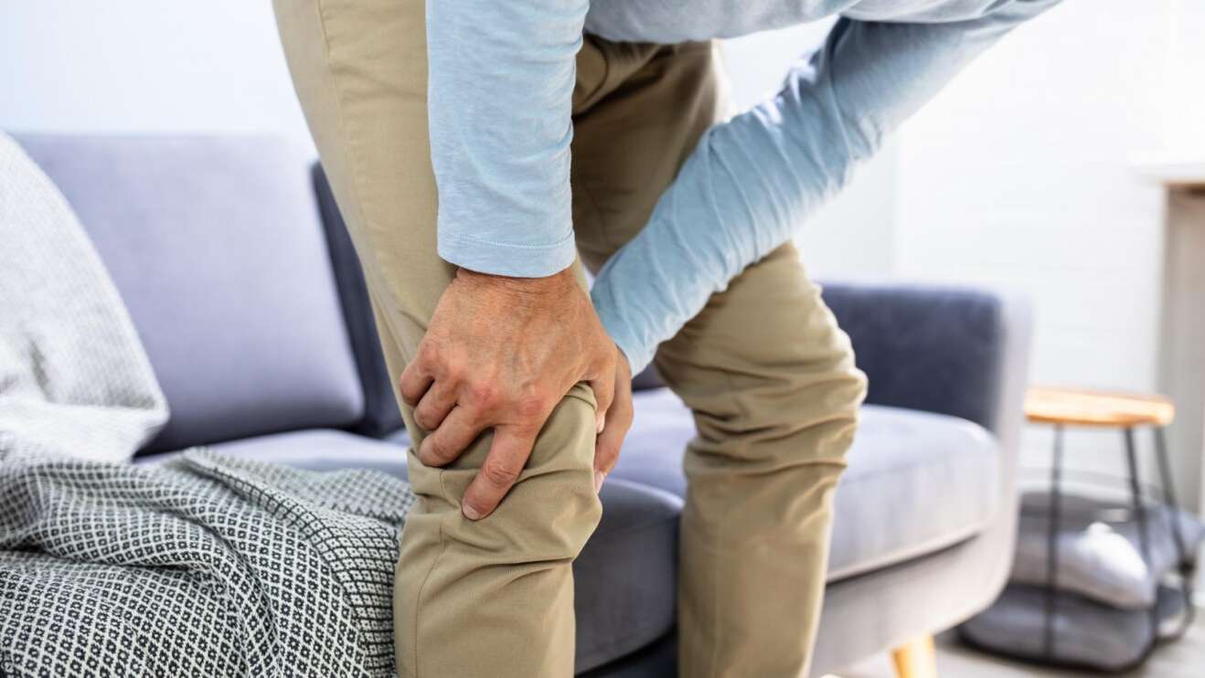 Ein Mann der sich vor Schmerzen das Knie hält