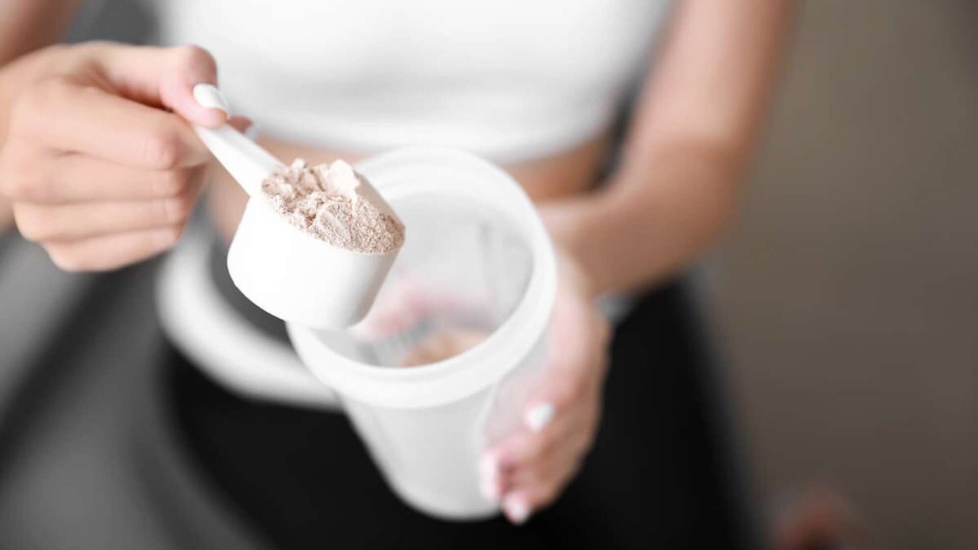 Ein Frau, die Whey-Protein in einen Shaker gibt