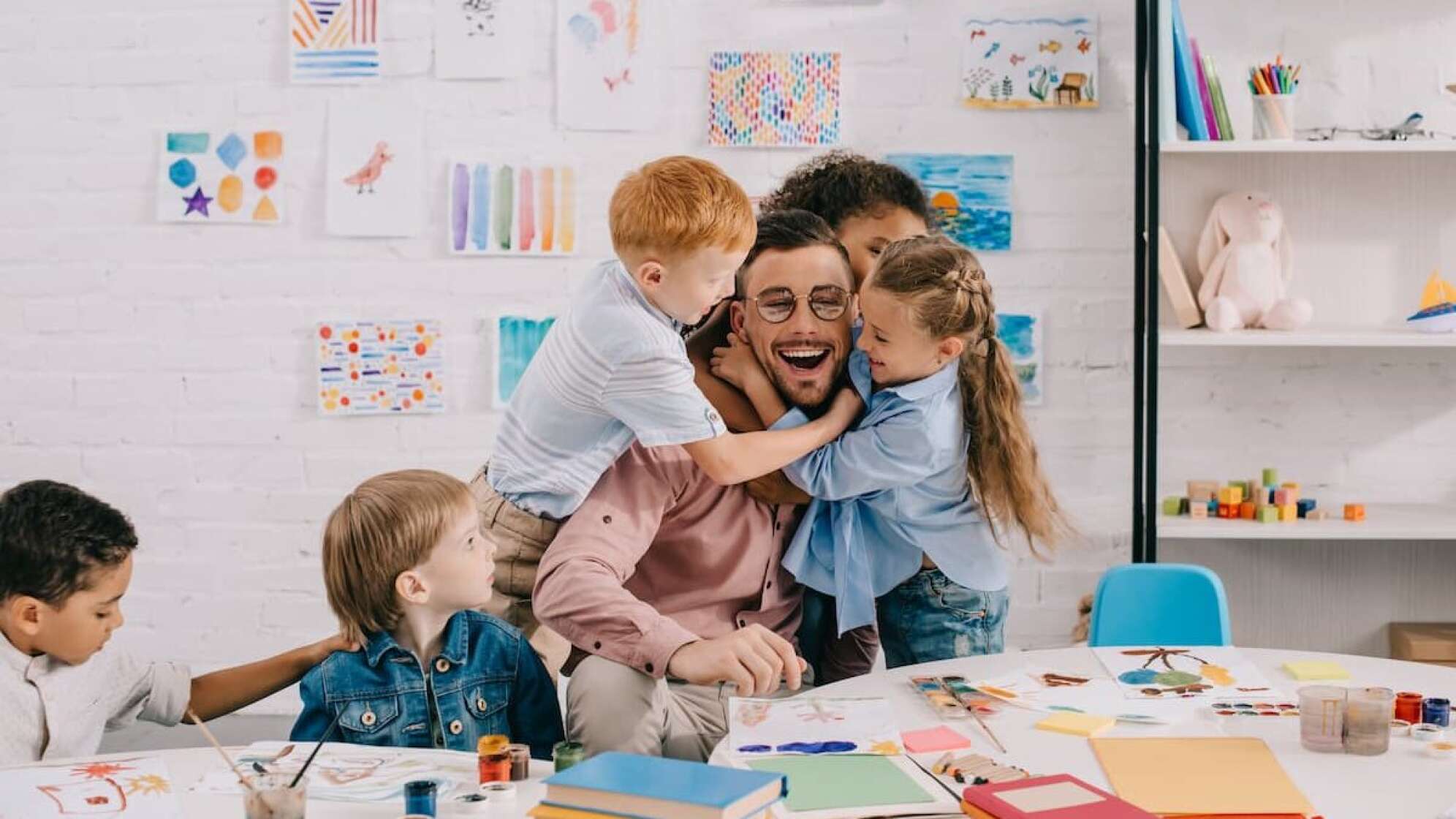 Ein Erzieher, der von Kinder umarmt wird