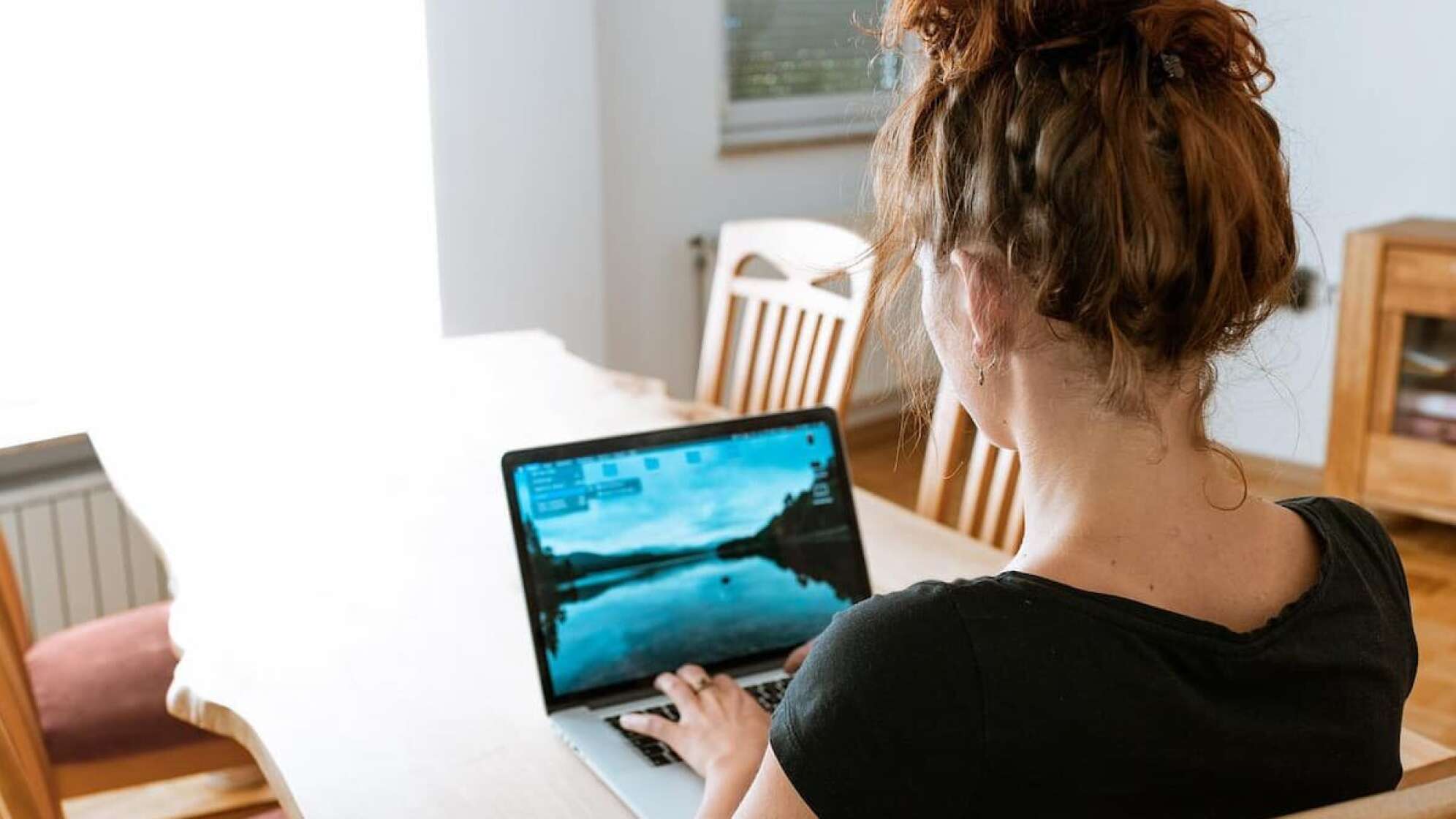 Eine Frau mit einem Laptop an einem Tisch sitzt