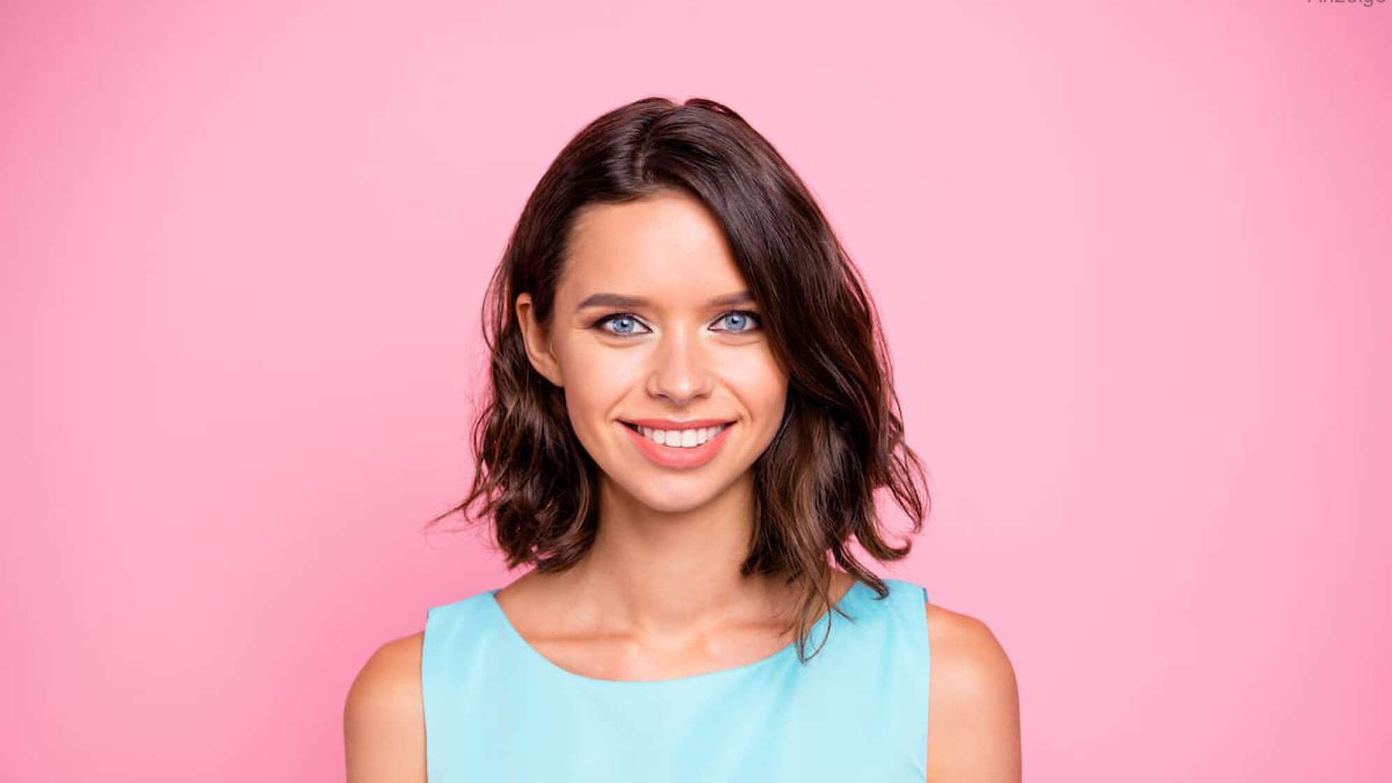 Eine Frau mit blauem Kleid vor pinkem Hintergrund