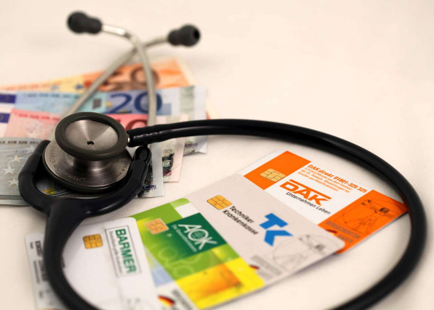 Stethoskop und Versichertenkarten verschiedener Krankenkassen