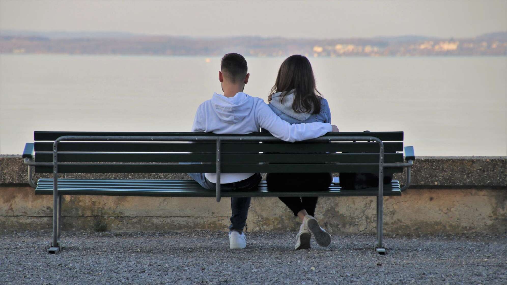 Ein Mann und eine Frau sitzen auf einer Bank am See