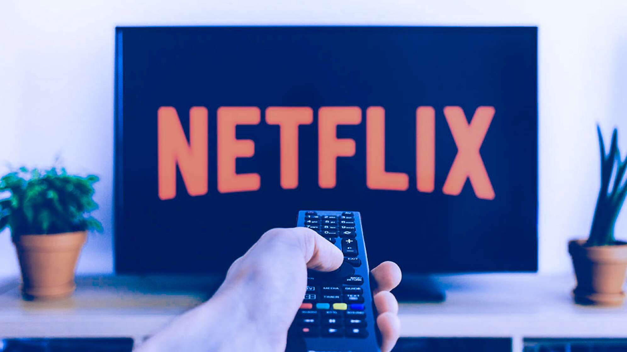 Ein TV Bildschirm mit dem Netflix Logo und eine Hand mit einer Fernbedinung
