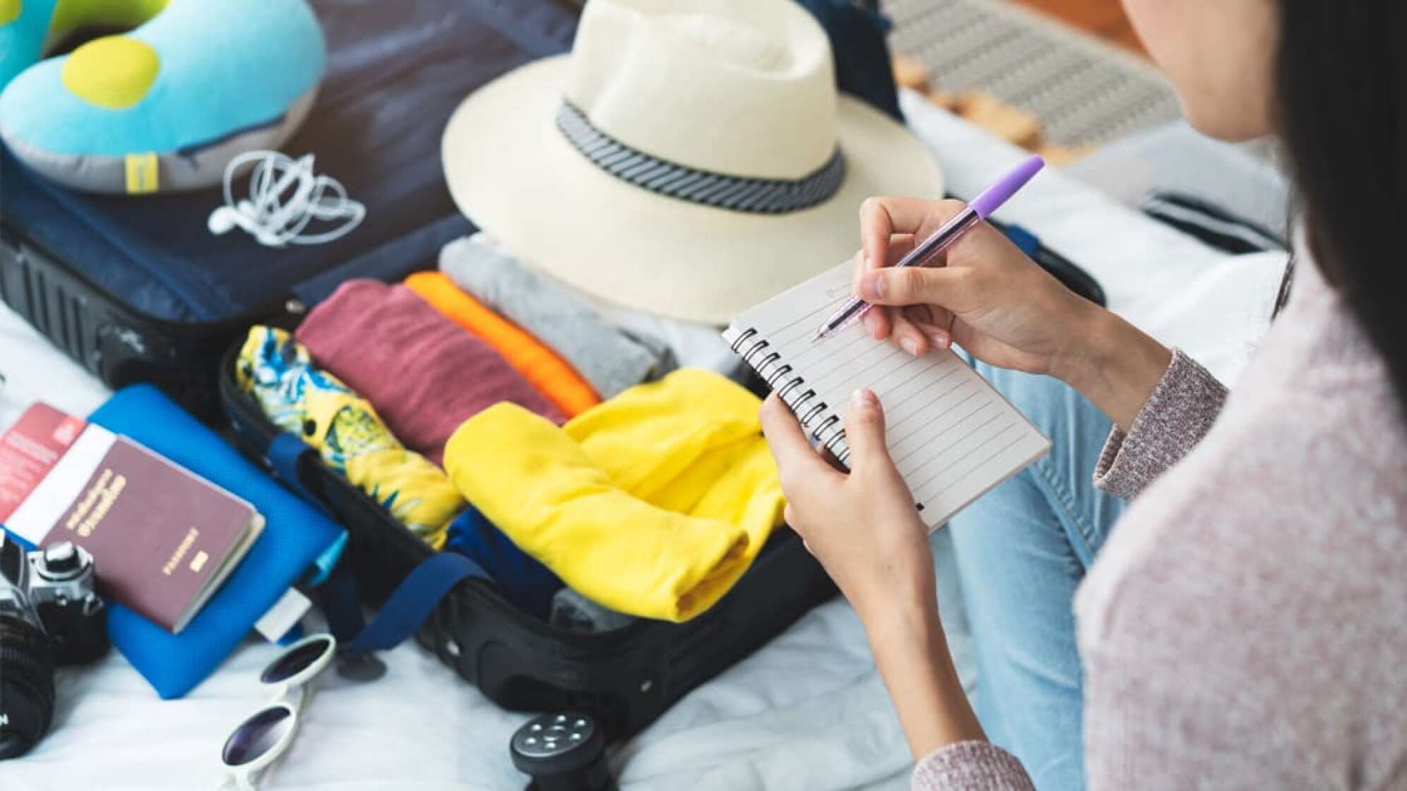 Aufschreiben von Notizen für die bevorstehende Reise mit Koffer in den Urlaub