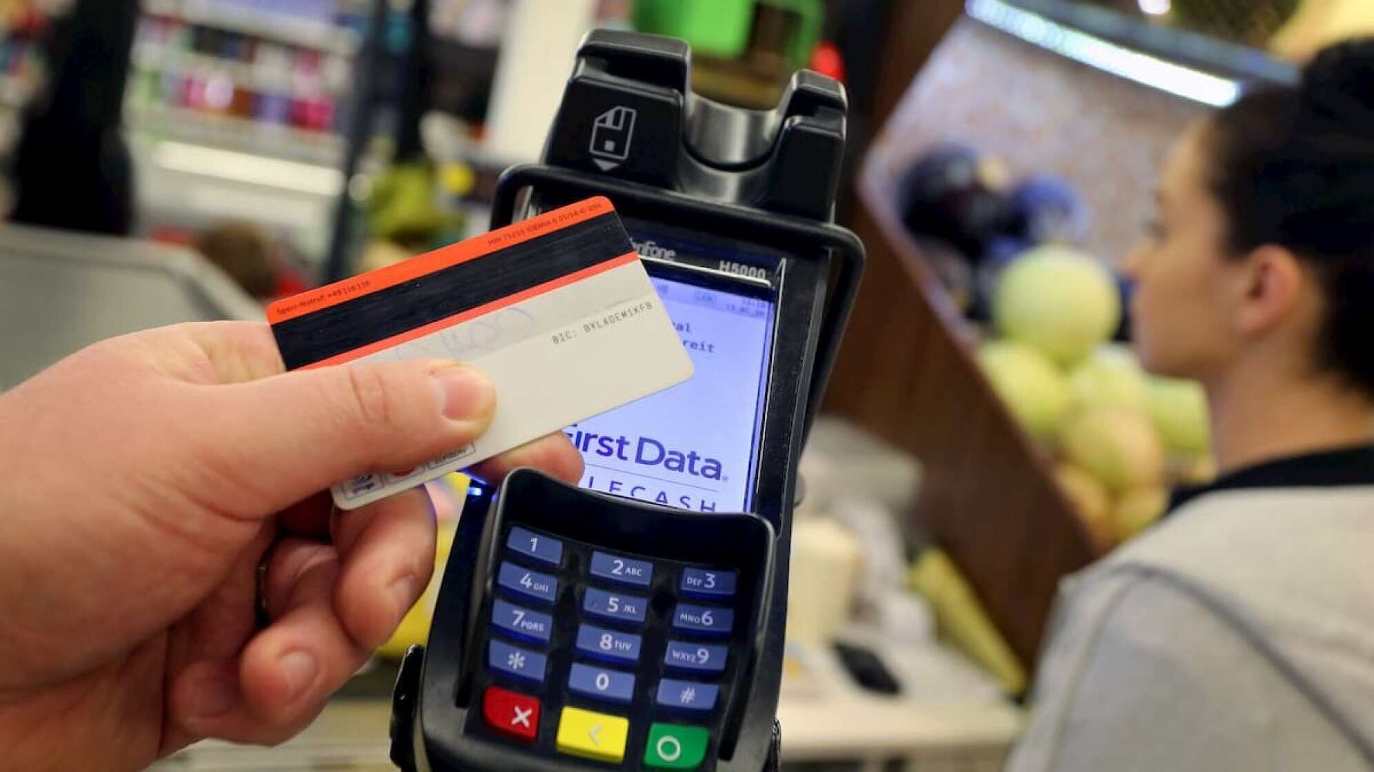 Eine Kreditkarte wird vor ein Kartenlesegerät gehalten in einem Supermarkt