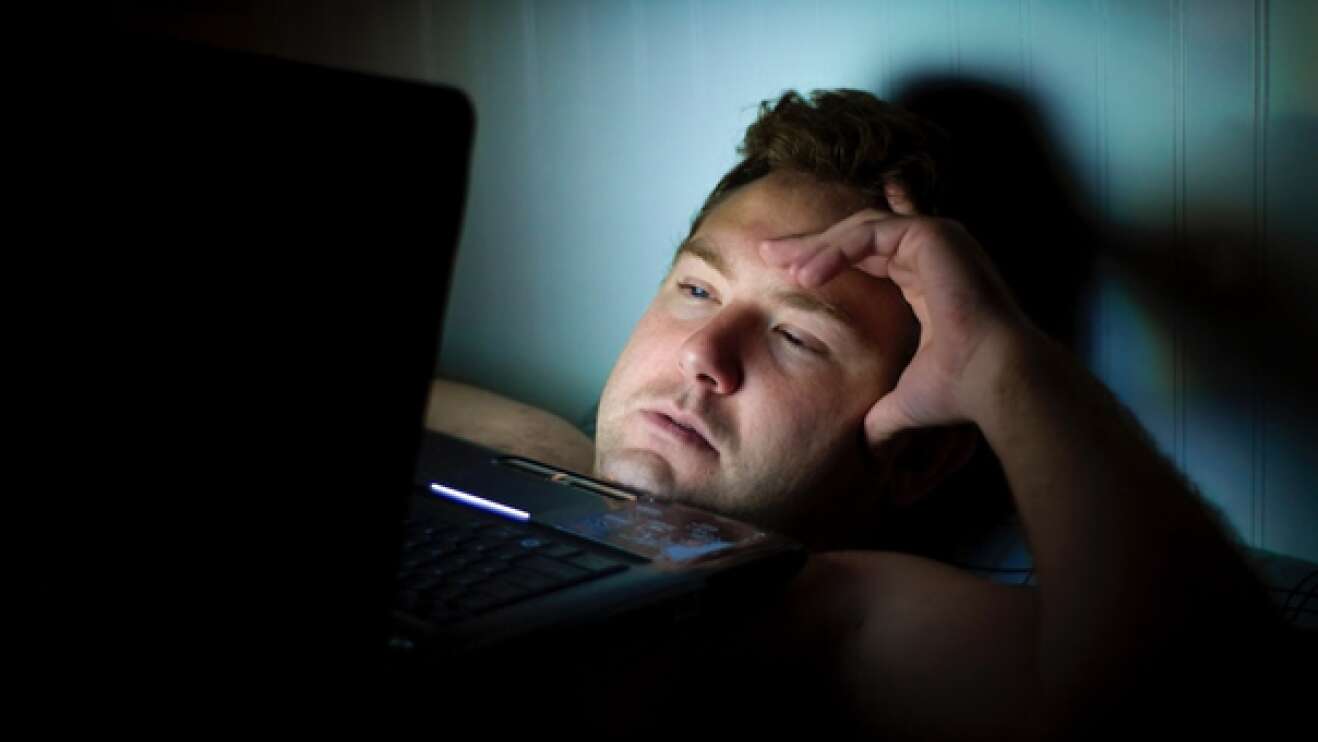 Mann mit Laptop im Bett