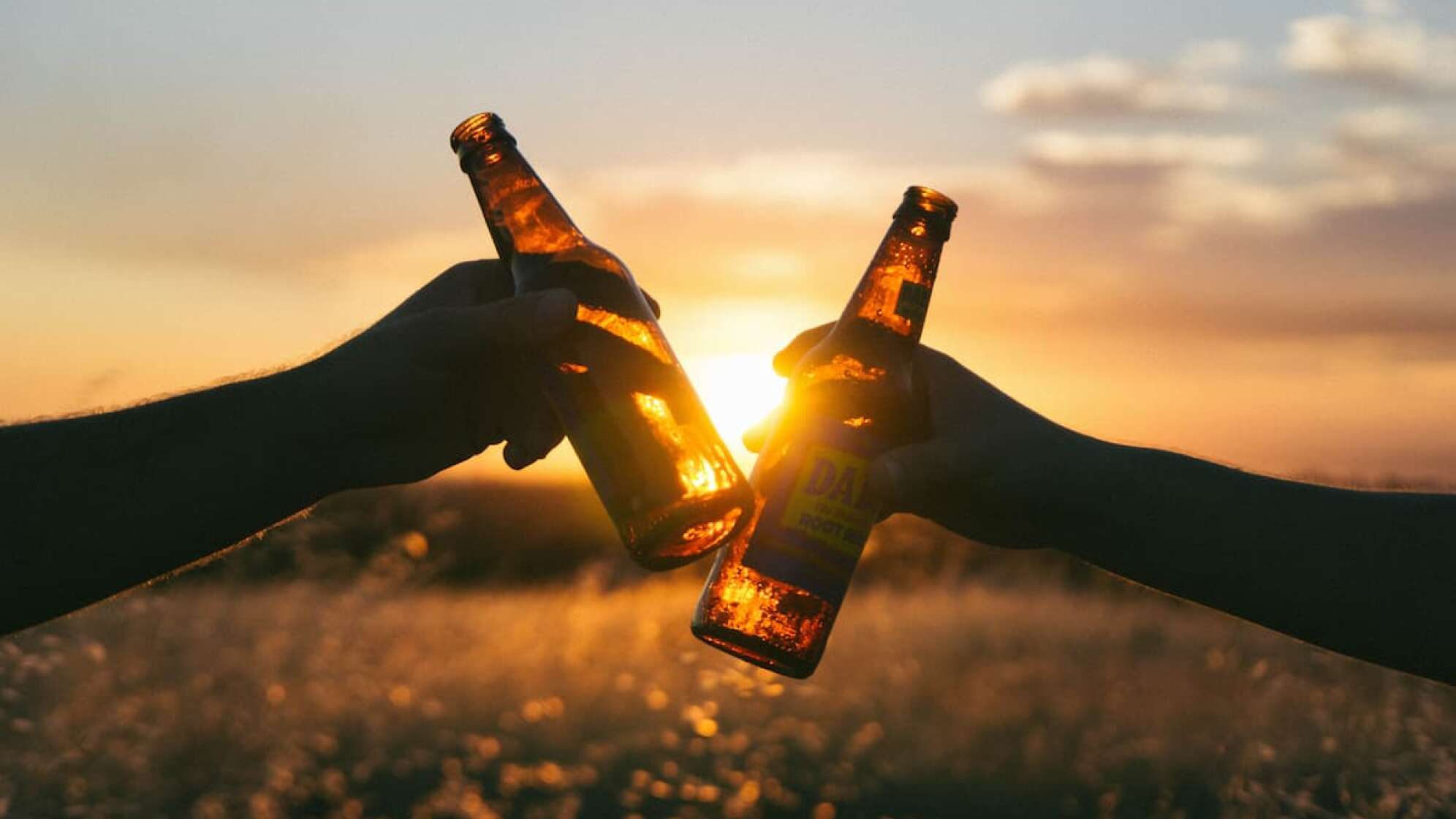 Mit zwei Bierflaschen in der Sonne anstoßen