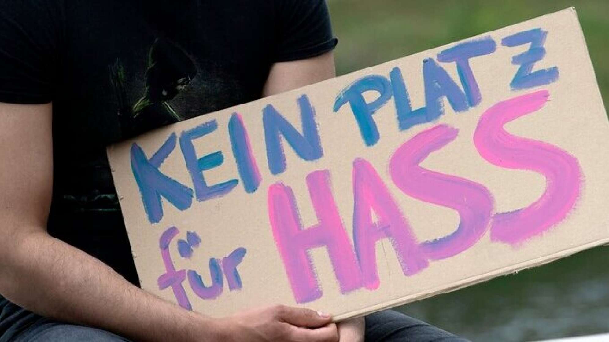 Ein Mann hält ein Schild mit der Aufschrift "Kein Platz für Hass"