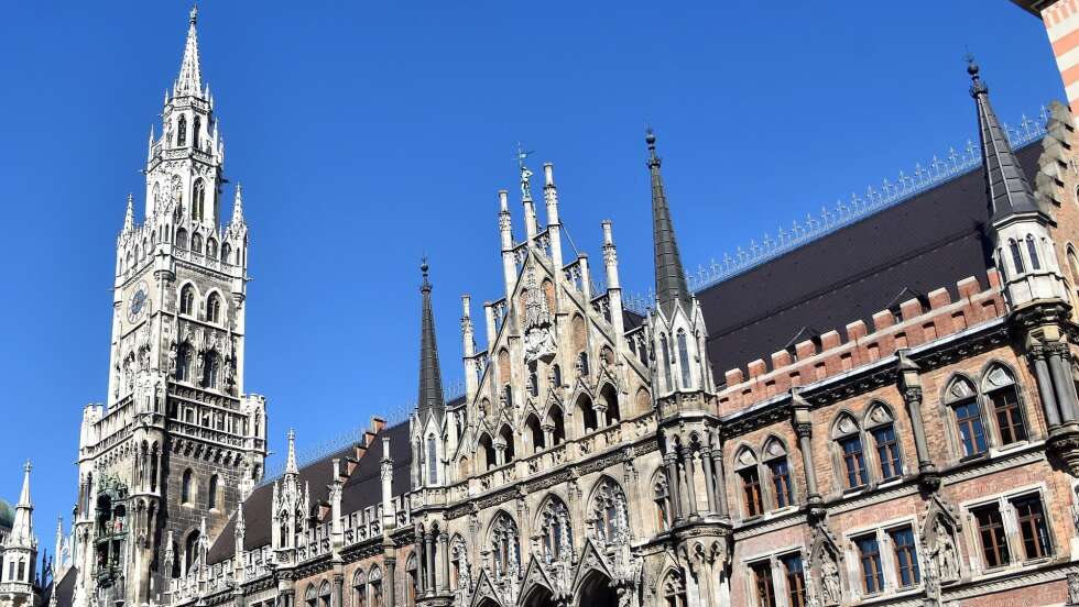 Neues Rathaus am Marienplatz in München mit Glockenspiel und gotischer Architektur bei blauem Himmel.