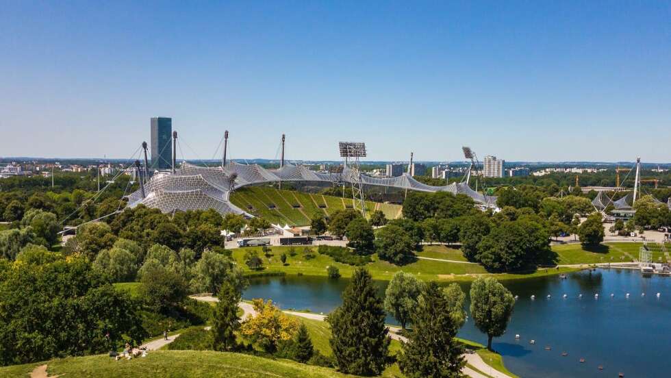 Olympiapark in München mit ikonischem Zeltdachstadion, umgeben von Grünflächen und Wasser.