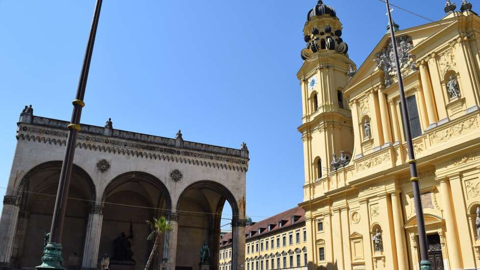 Odeonsplatz in München mit Feldherrnhalle und Theatinerkirche bei sonnigem Wetter und blauem Himmel.