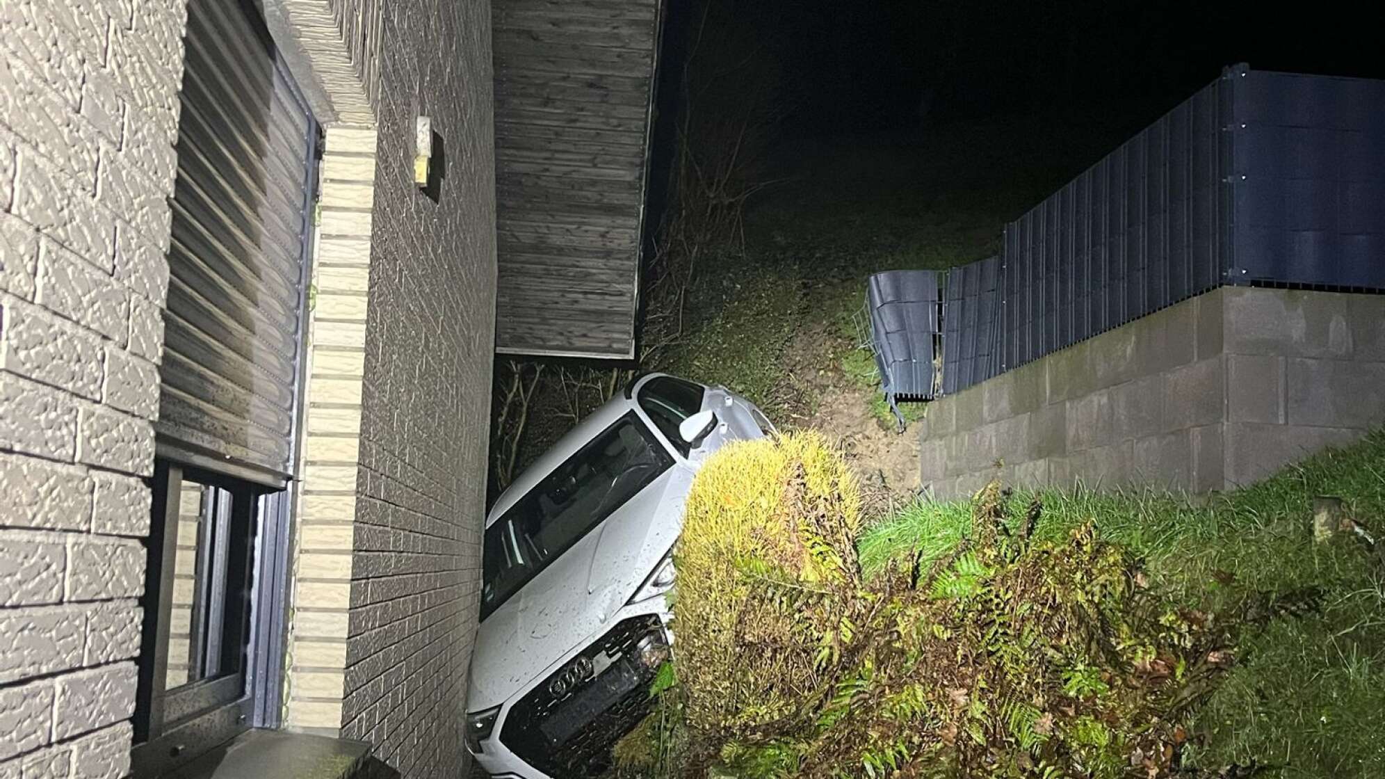 Autofahrerin rutscht den Abhang hinunter in ein Haus